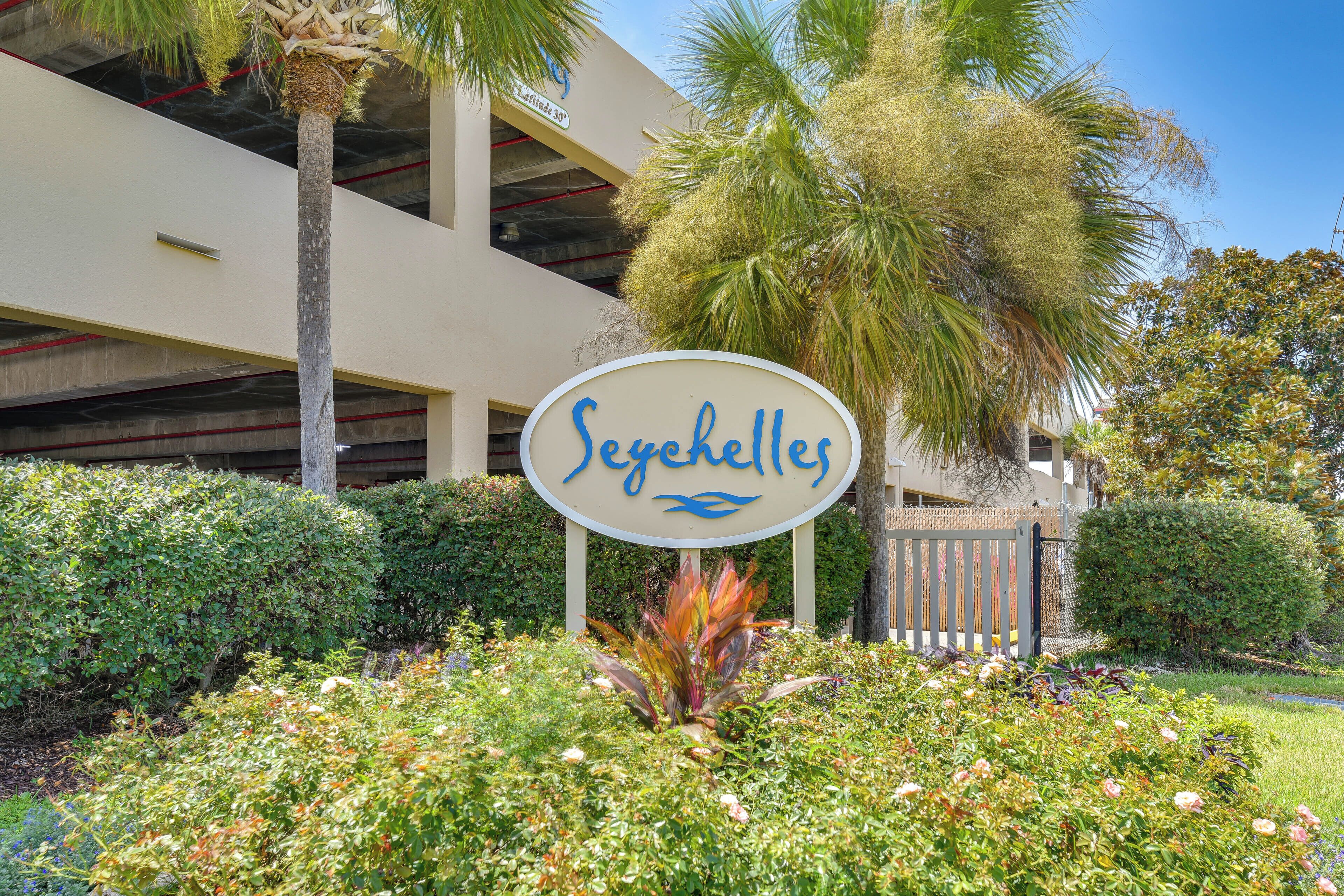 A sign with the name 'Seychelles' surrounded by lush greenery and a palm tree.