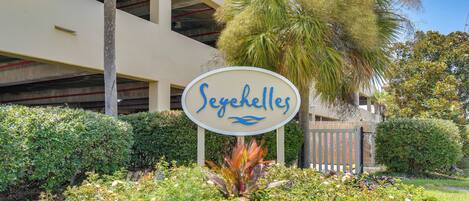 A sign with the name 'Seychelles' surrounded by lush greenery and a palm tree.