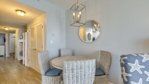 Een eetgedeelte met rieten stoelen, een ronde tafel en een spiegel aan de wand.