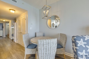 A dining area with wicker chairs, a round table, and a mirror on the wall. - Gulf Views & Beach Access! 2 PCB Condos w/ Pool! (Panama City Beach)
