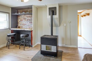 Ein Zimmer mit Kamin, einer Bar mit Hockern und Holzboden.