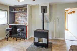 Una habitación con chimenea, una zona de bar con taburetes y suelo de madera.