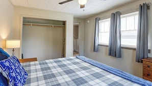 A bedroom with a bed, a nightstand, a lamp, a closet, and a window with curtains. - Walk to Park & Creek! Spearfish Couples Retreat (Spearfish)