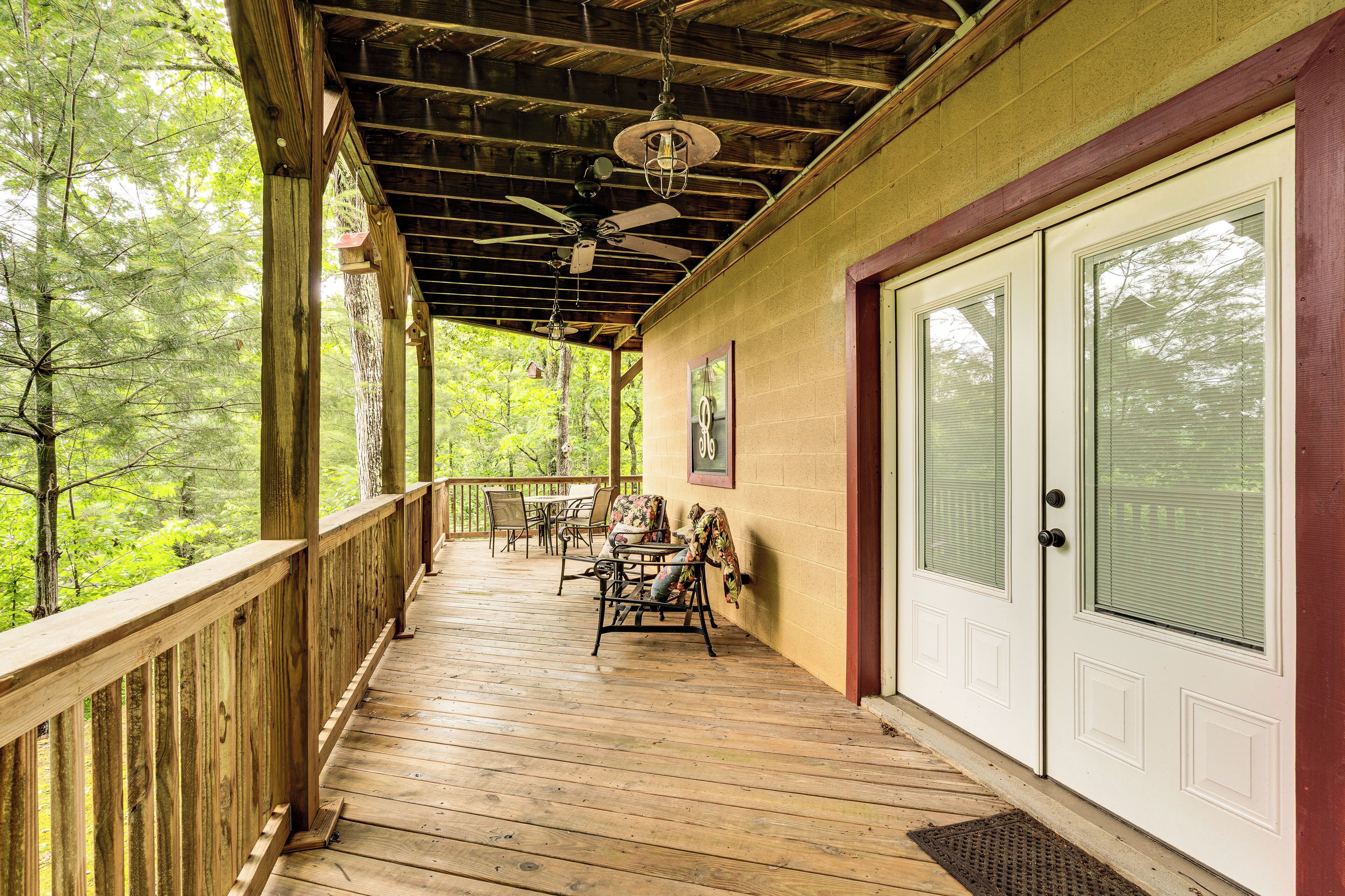 A wooden deck with a ceiling fan, a table with chairs, and a door with a window.