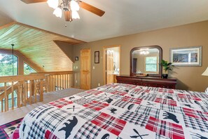Un dormitorio con una cama grande, techo de madera, una escalera y vistas al exterior.