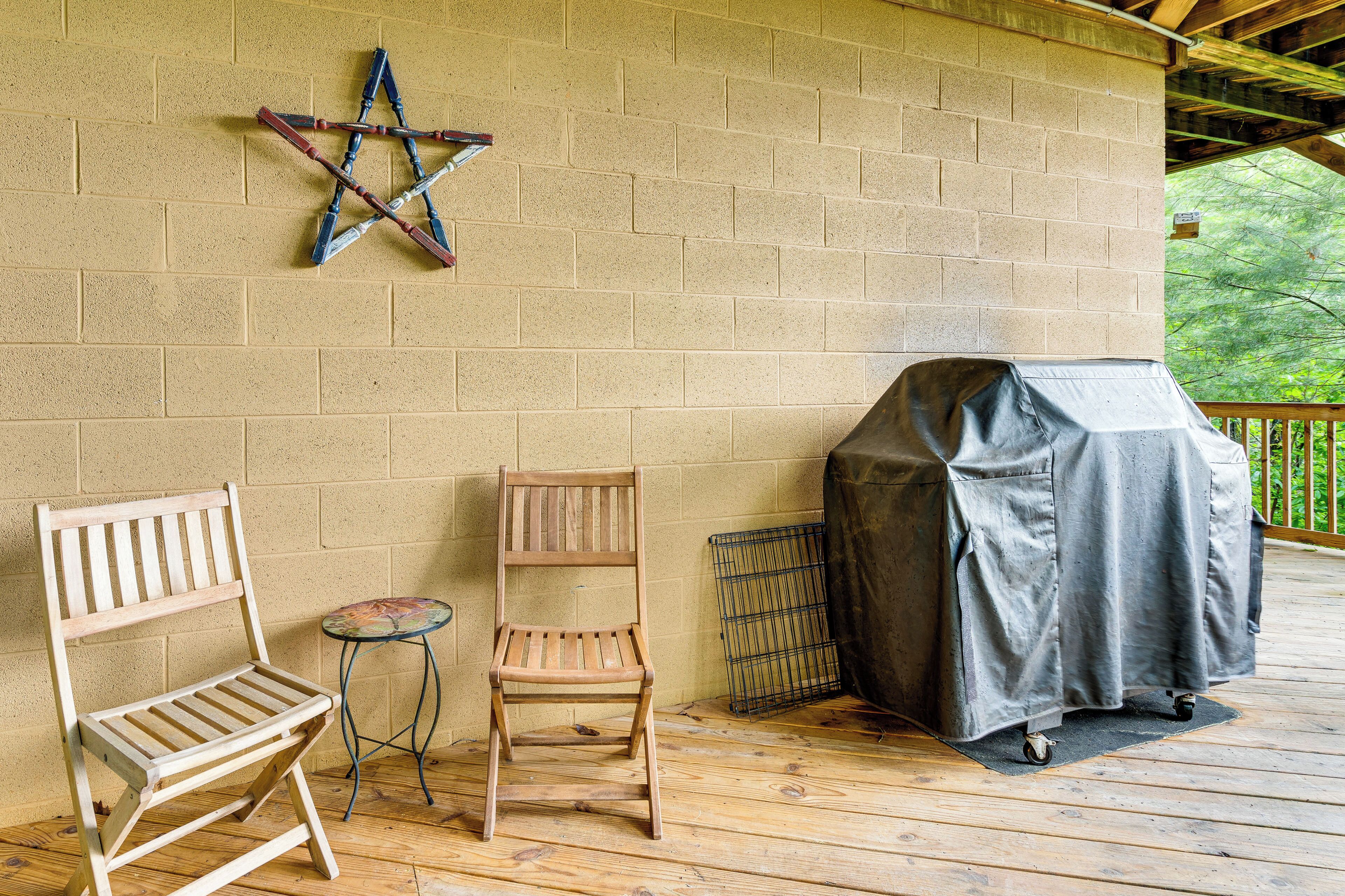 A covered outdoor seating area with a wooden bench, a chair, and a grill.