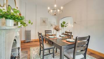 A dining room with a marble fireplace, a chandelier, and a large mirror.