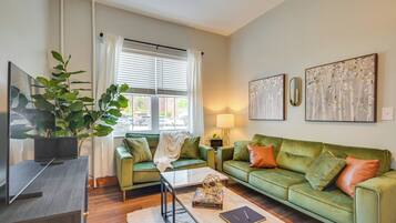 A living room with a green sofa, a coffee table, a TV, and a large plant.