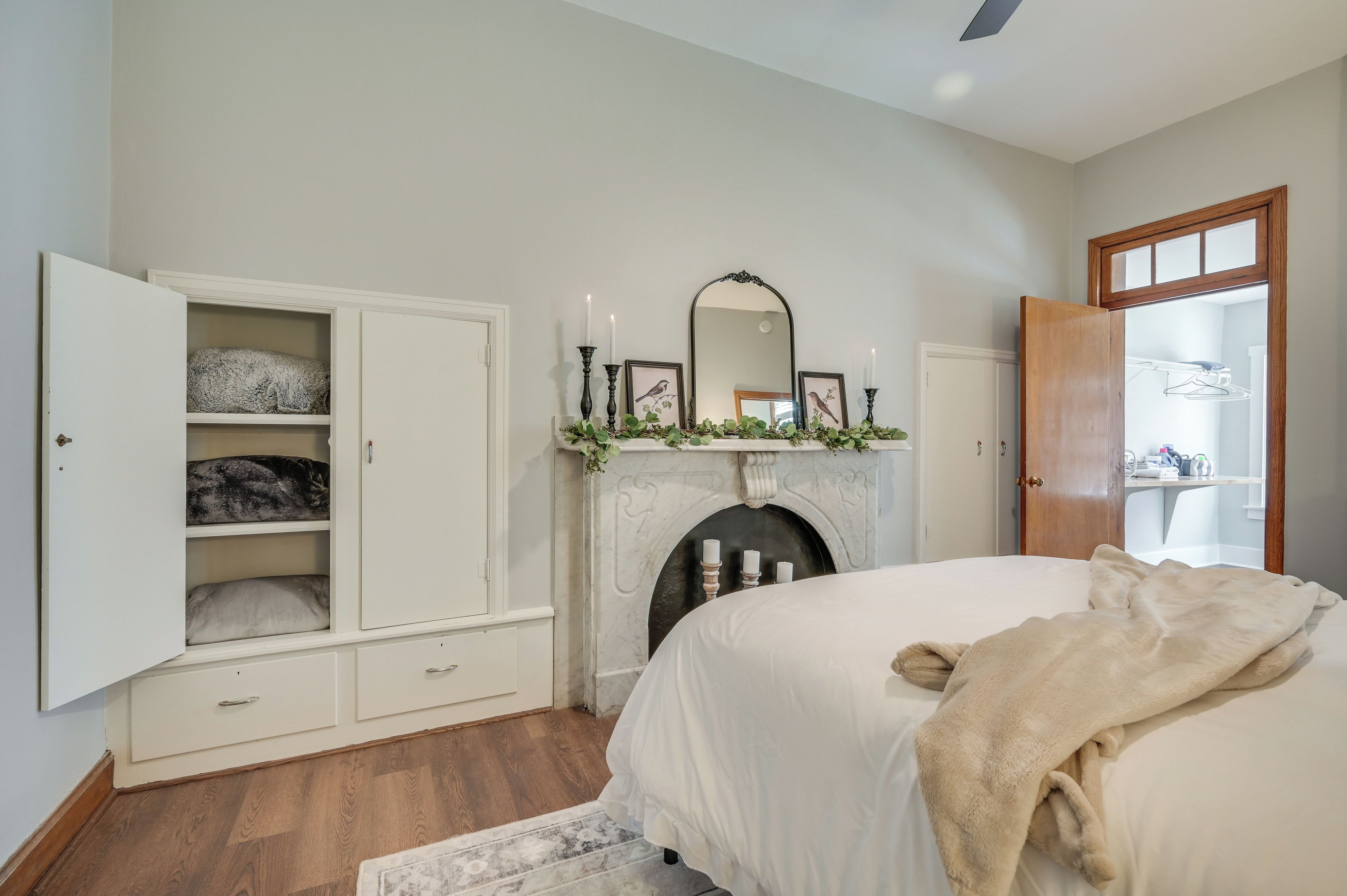 A bedroom with a bed, a wardrobe, a fireplace, and a mirror.