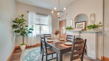 A dining room with a wooden table, chairs, a chandelier, a potted plant, and a fireplace with a sign reading "Pennsylvania".