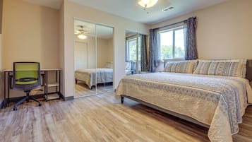 Un dormitorio con una cama grande, una silla, un espejo y un ventilador de techo.