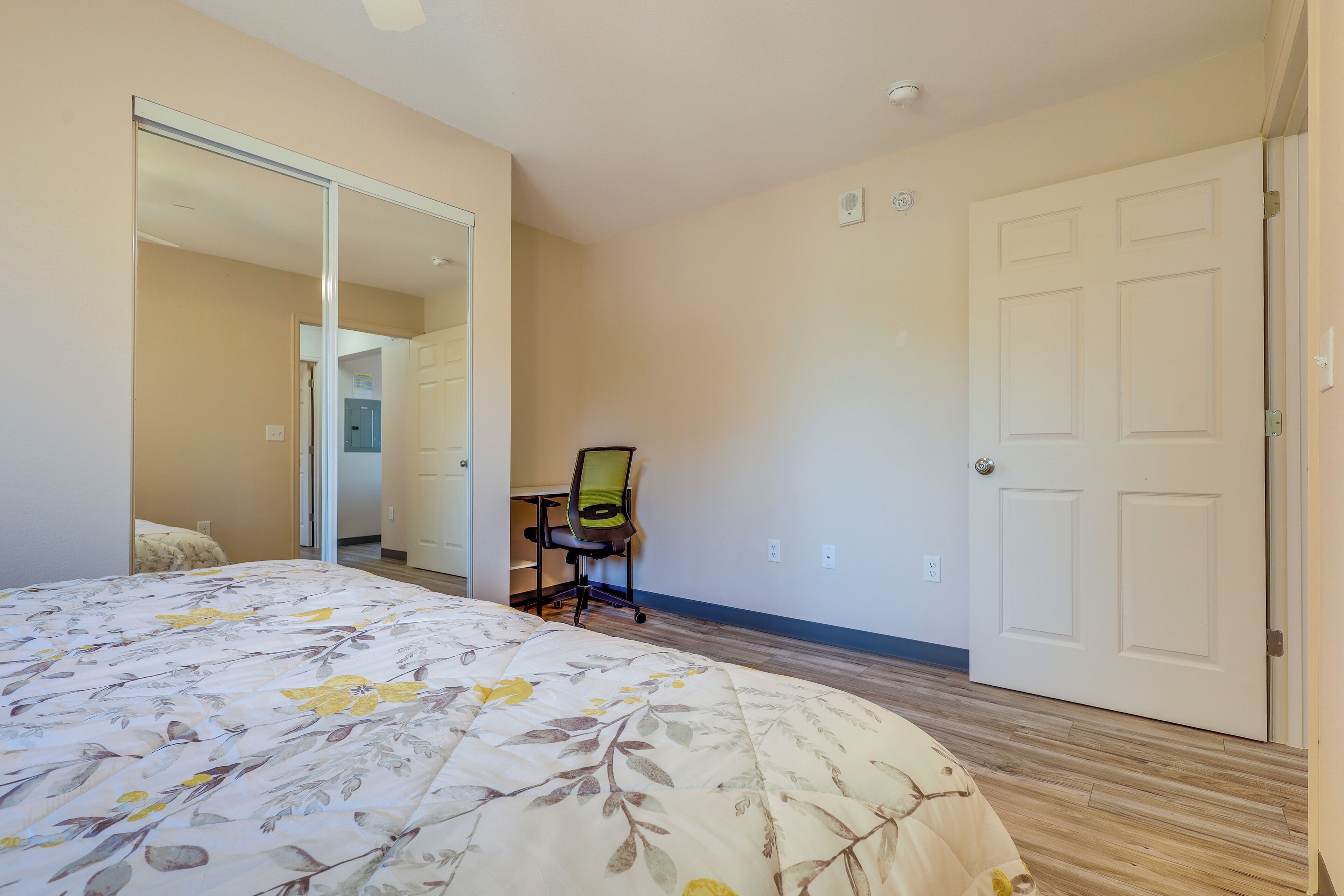 A bedroom with a bed, a chair, a wardrobe, and a door.