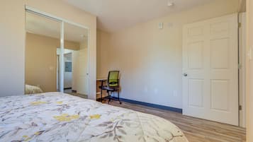 A bedroom with a bed, a chair, a wardrobe, and a door.