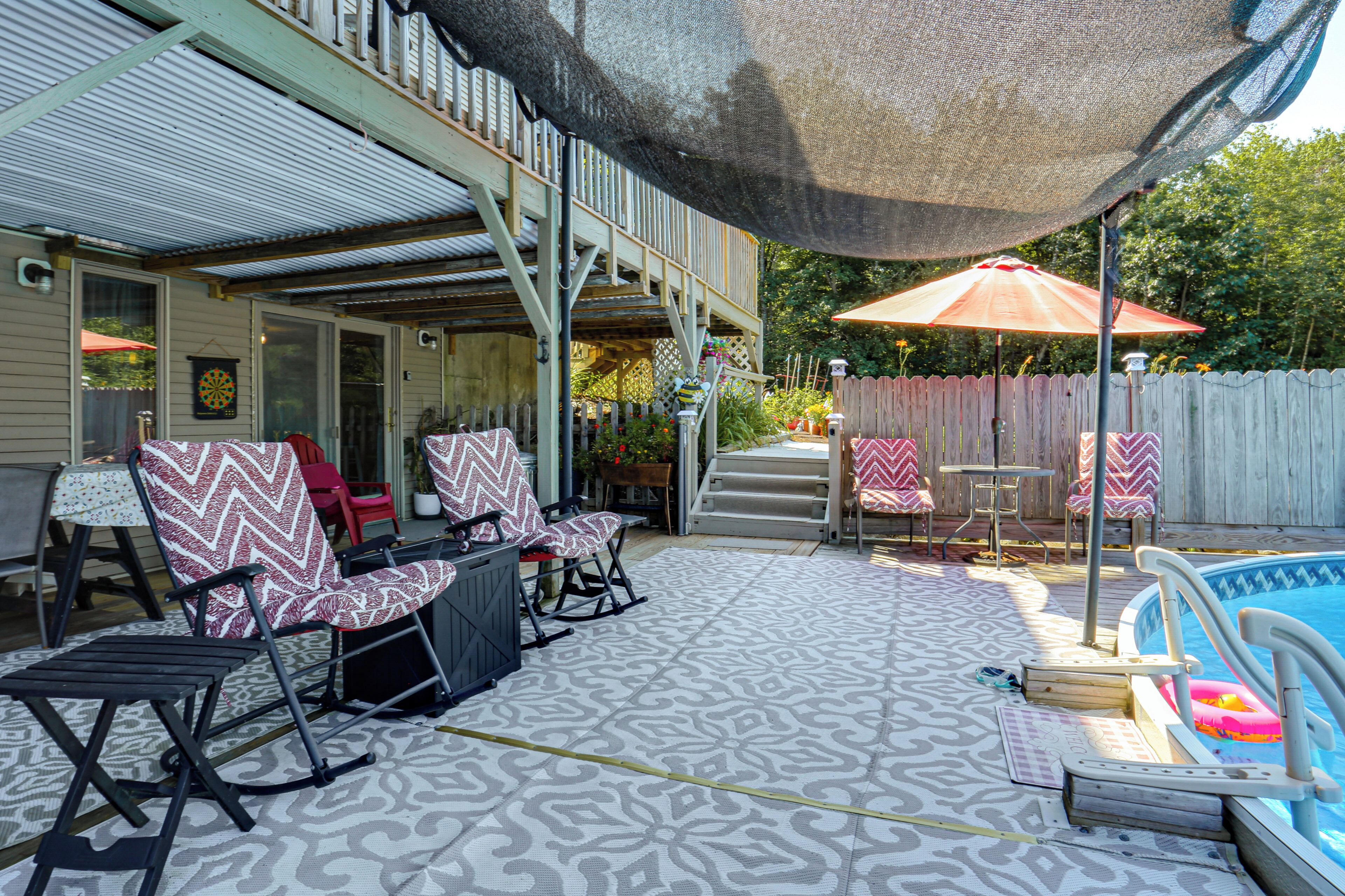 Een achtertuin met een overdekte patio, buitenmeubels en een zwembad.