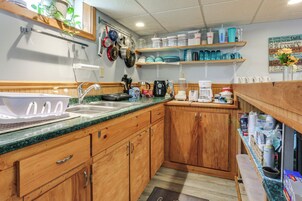 Una cocina con armarios de madera, un lavamanos y diversos electrodomésticos.