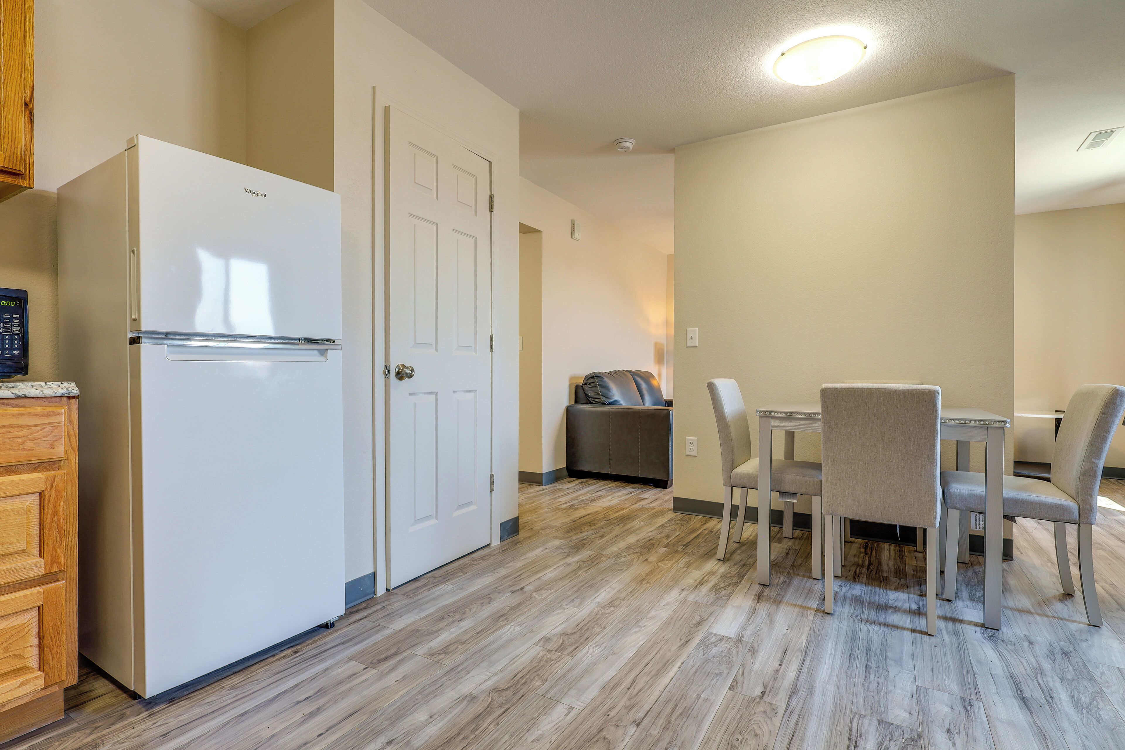 A compact kitchen with a refrigerator, double doors, and a dining area with a table and chairs.