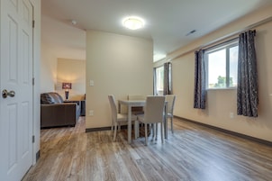 Una habitación con una mesa de comedor, sillas, un sofá y una ventana con cortinas.
