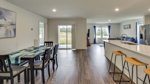 Eine moderne Küche mit Kochinsel, Barhocker und einem Essbereich mit Tisch und St ühlen.