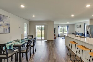Eine moderne Küche mit Kochinsel, Barhocker und einem Essbereich mit Tisch und Stühlen.