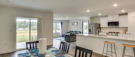 A modern kitchen with a central island, bar stools, and a dining area with a table set for two.