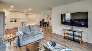 Ein modernes Wohnzimmer mit grauem Sofa, Couchtisch und flachbildfernseher an der Wand.