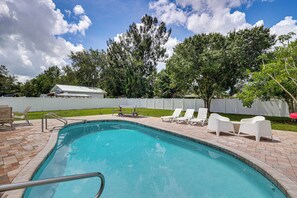 A swimming pool with a metal ladder, surrounded by white lounge chairs and a white fence. - Mid-term Stay in Sarasota! Home w/ Pool & Hot Tub (Sarasota)