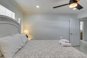 A bedroom with a bed, a nightstand, a lamp, a ceiling fan, and a door leading to another room. - Mid-term Stay in Sarasota! Home w/ Pool & Hot Tub (Sarasota)