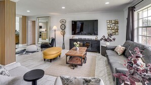 Uma sala de estar moderna com sofá, banqueta, mesa de centro e lareira.
