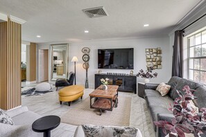 A modern living room with a sofa, ottoman, coffee table, and a fireplace. - Mid-term Stay in Sarasota! Home w/ Pool & Hot Tub (Sarasota)