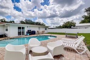 A swimming pool with lounge chairs and a table, surrounded by a brick patio. - Mid-term Stay in Sarasota! Home w/ Pool & Hot Tub (Sarasota)