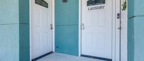 A set of white doors with a label 'LAUNDRY' on one of them, a small wall-mounted light fixture, and a small step leading to the entrance.