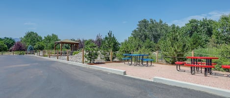 A paved road with picnic tables and a gazebo in a park.