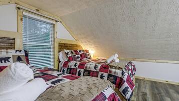 A bedroom with two beds, a window with blinds, and a sloped ceiling.