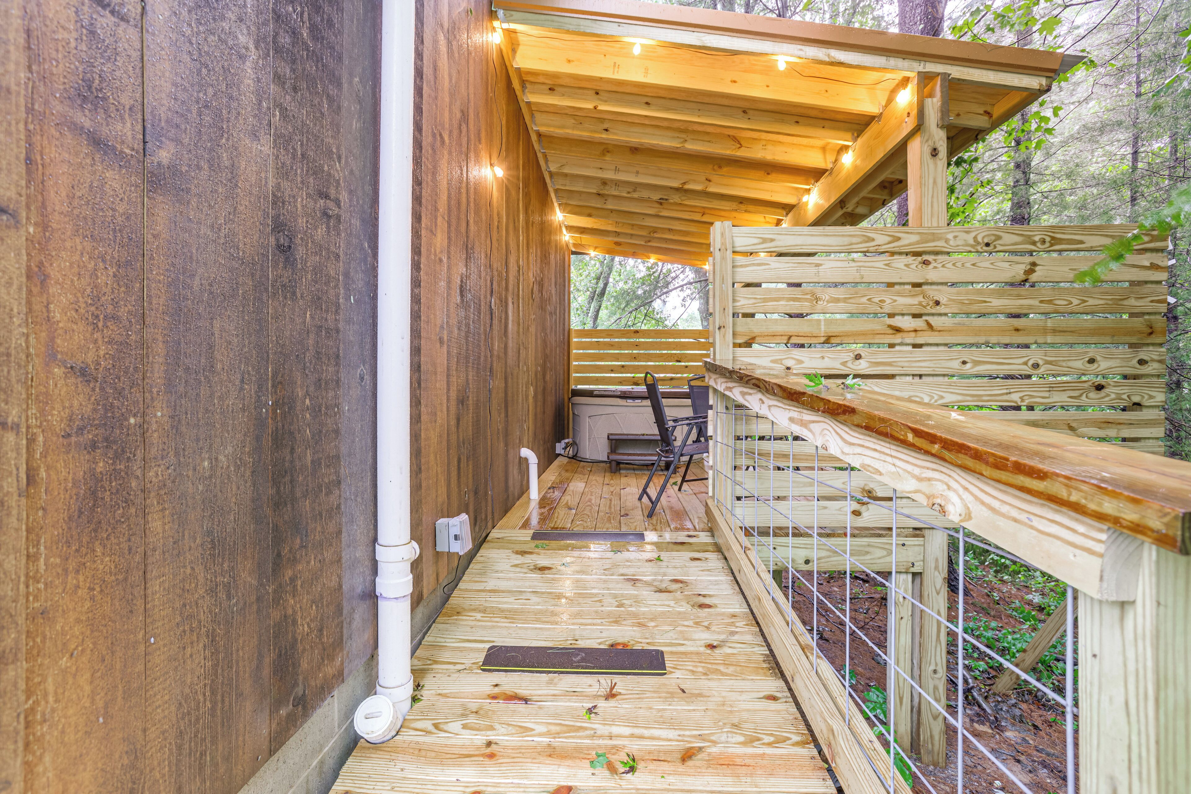A wooden deck with a metal railing, a white pipe, and a bench.
