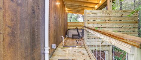 A wooden deck with a metal railing, a white pipe, and a bench.