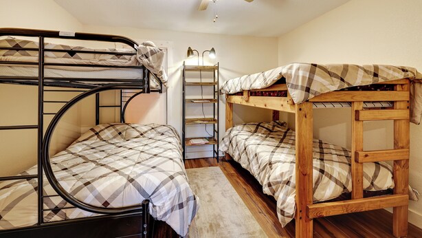 A dormitory room with bunk beds, a ceiling fan, and a desk with a lamp. - Golf, Beaches, Slopes & More! Thompsonville Home (Thompsonville)