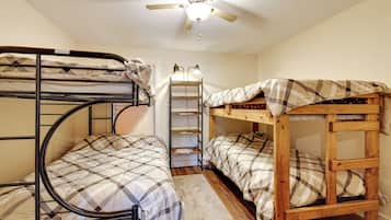 Une chambre de dortoir avec des lits superposés, un ventilateur de plafond et un bureau avec une lampe.