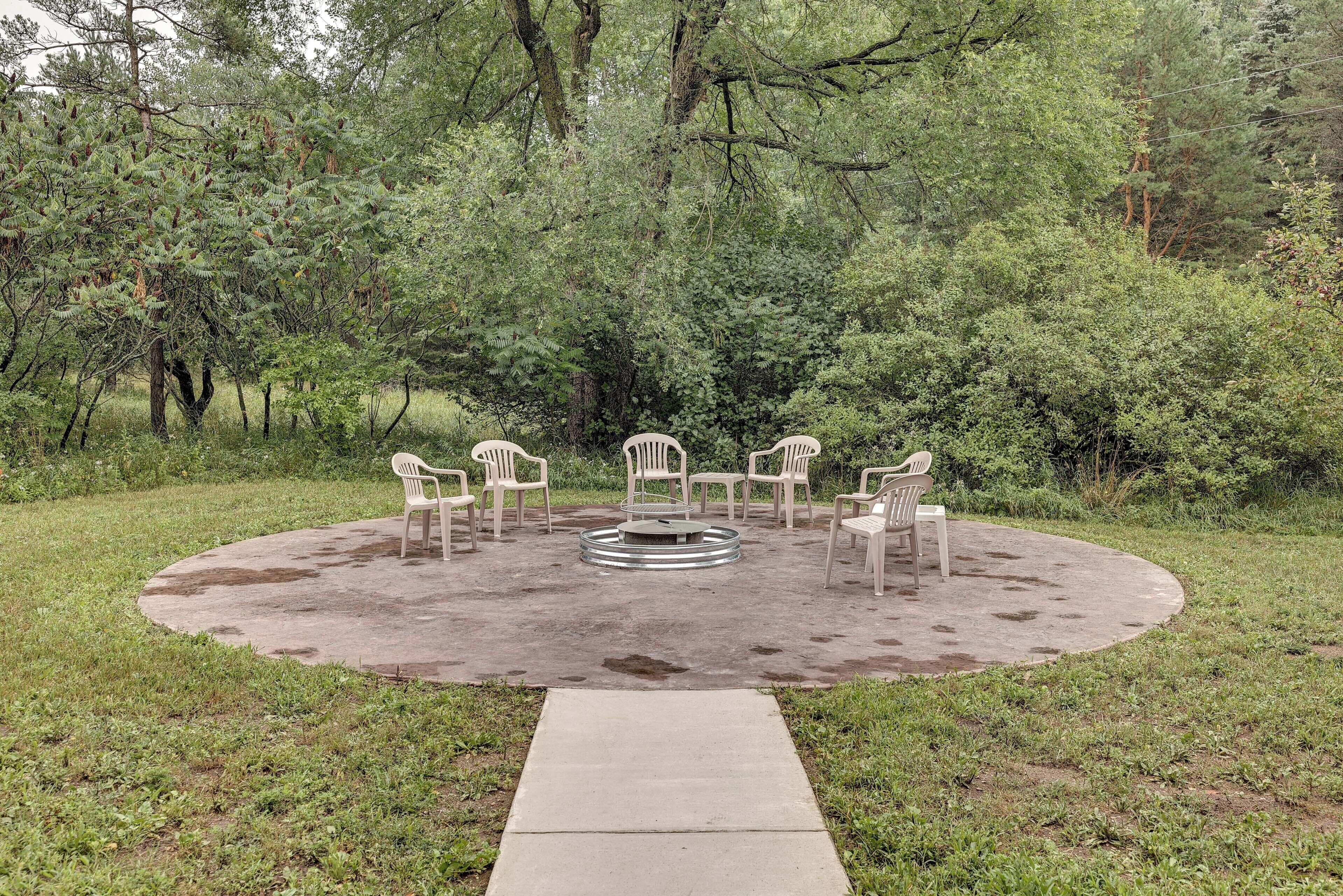 Un espace extérieur aménagé avec des chaises disposées autour d’une table centrale, le tout étant entouré d’un cercle en béton sur un terrain herbeux.