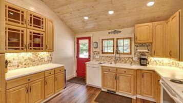 A kitchen with wooden cabinets, a red door, and a stone backsplash.