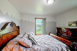 Quarto com cama, penteadeira e janela com cortinas.