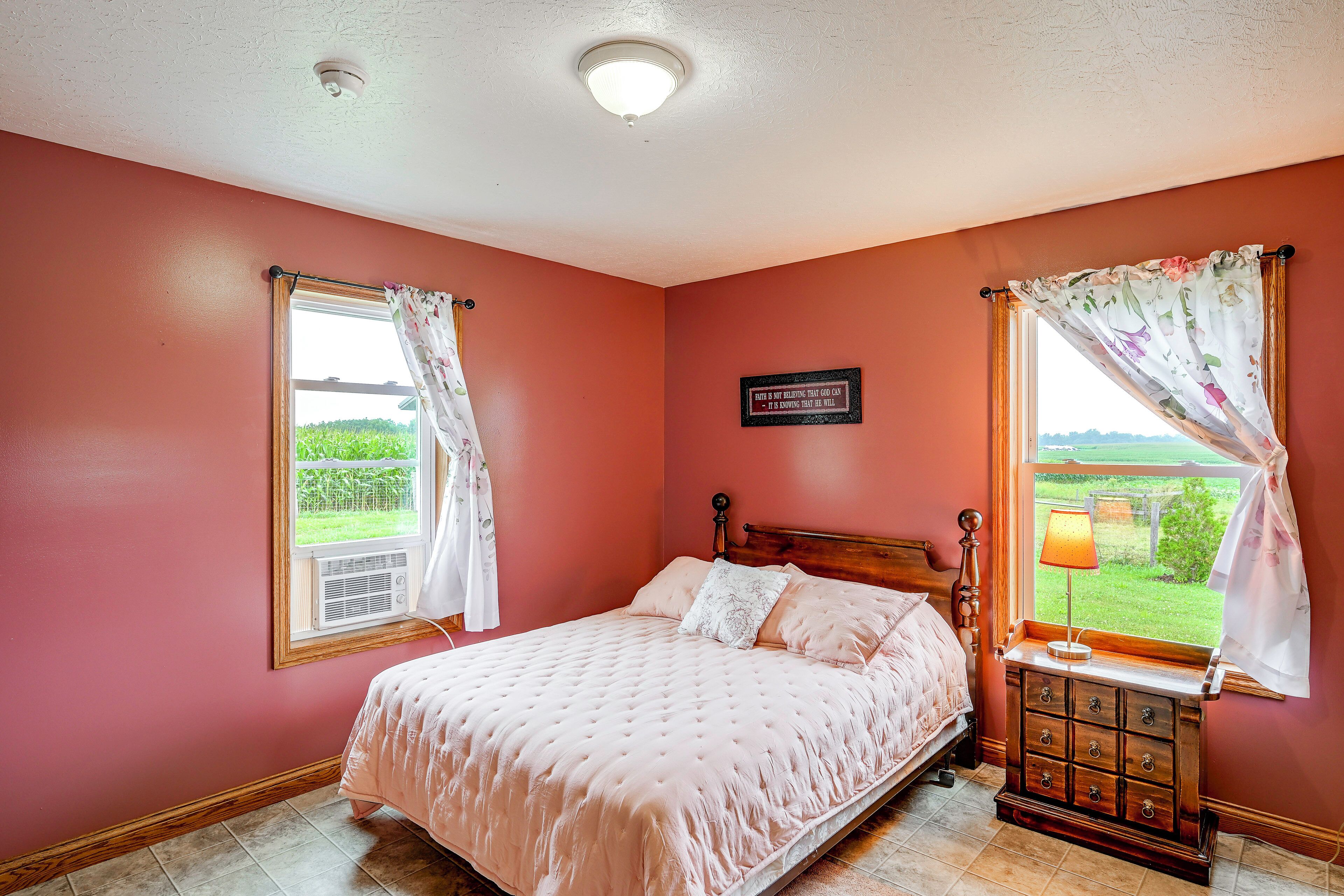 A bedroom with a bed, a nightstand, a lamp, and a window with curtains.