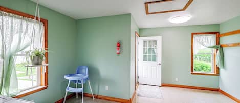 A room with a green wall, a white door, a blue chair, and a window with a curtain.