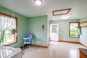 Una habitación con pared verde, puerta blanca, silla azul y ventana con cortina.