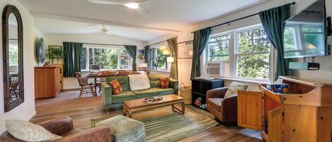 Ein geräumiges Wohnzimmer mit Sofa, Sesseln, Couchtisch und Fernseher.