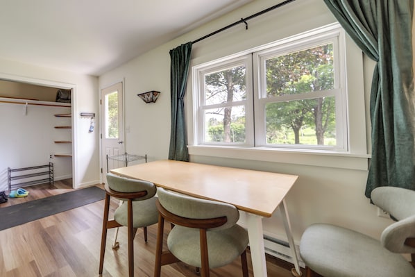 A room with a wooden table and two chairs, a window with curtains, and a door leading to another room. - Deck & Stunning Views! Family Getaway in Hamilton (Hamilton)
