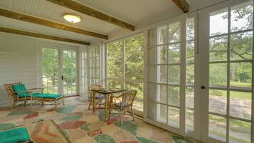 A room with large windows, a table with chairs, and a patterned floor.