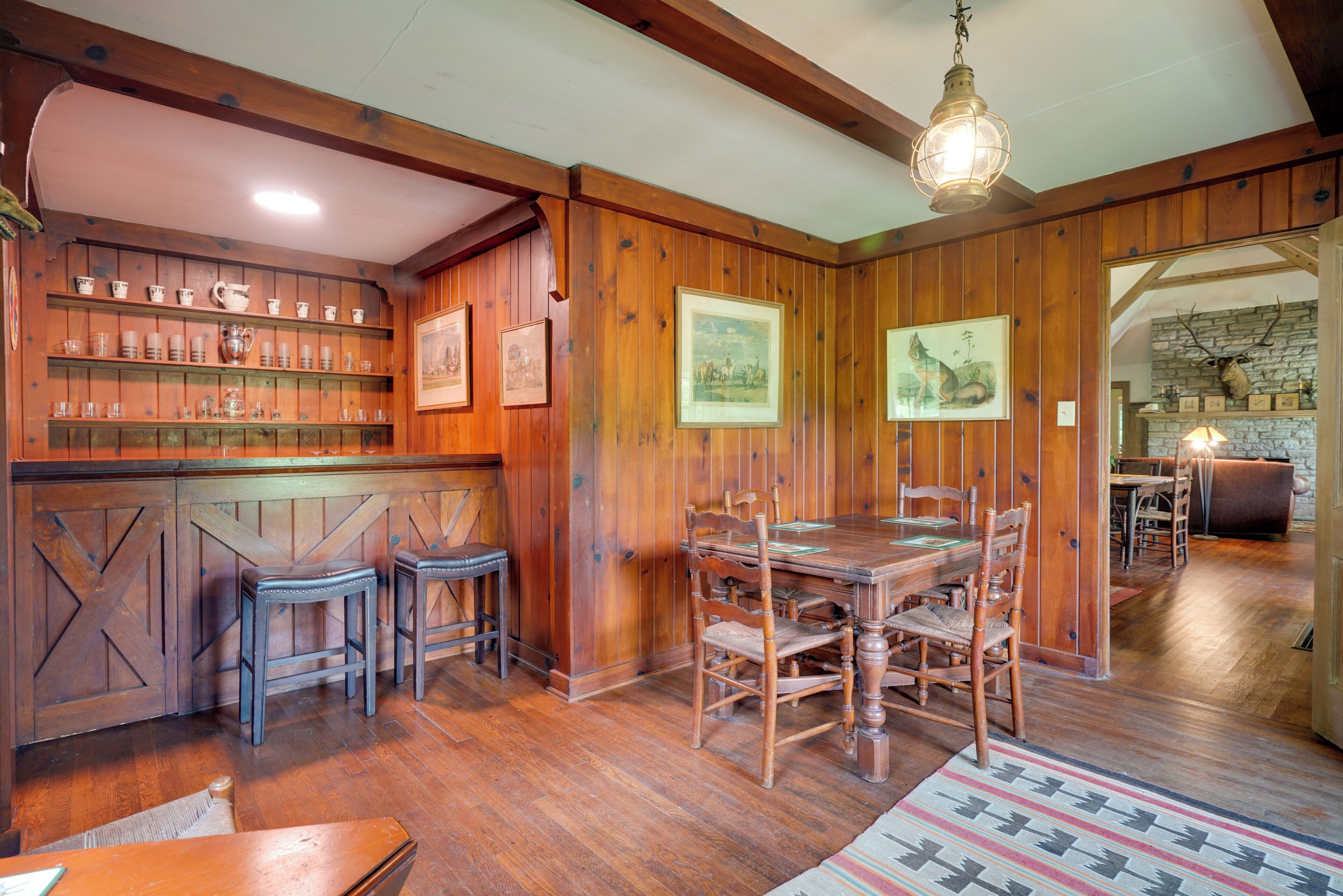 A wooden interior with a bar area, dining table, and chairs.