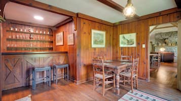 A wooden interior with a bar area, dining table, and chairs.