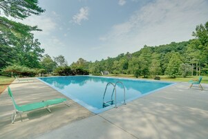 Piscina retangular com trampolim e cadeiras de descanso.