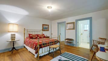A bedroom with a bed, bedside table, lamp, and a door leading to another room.